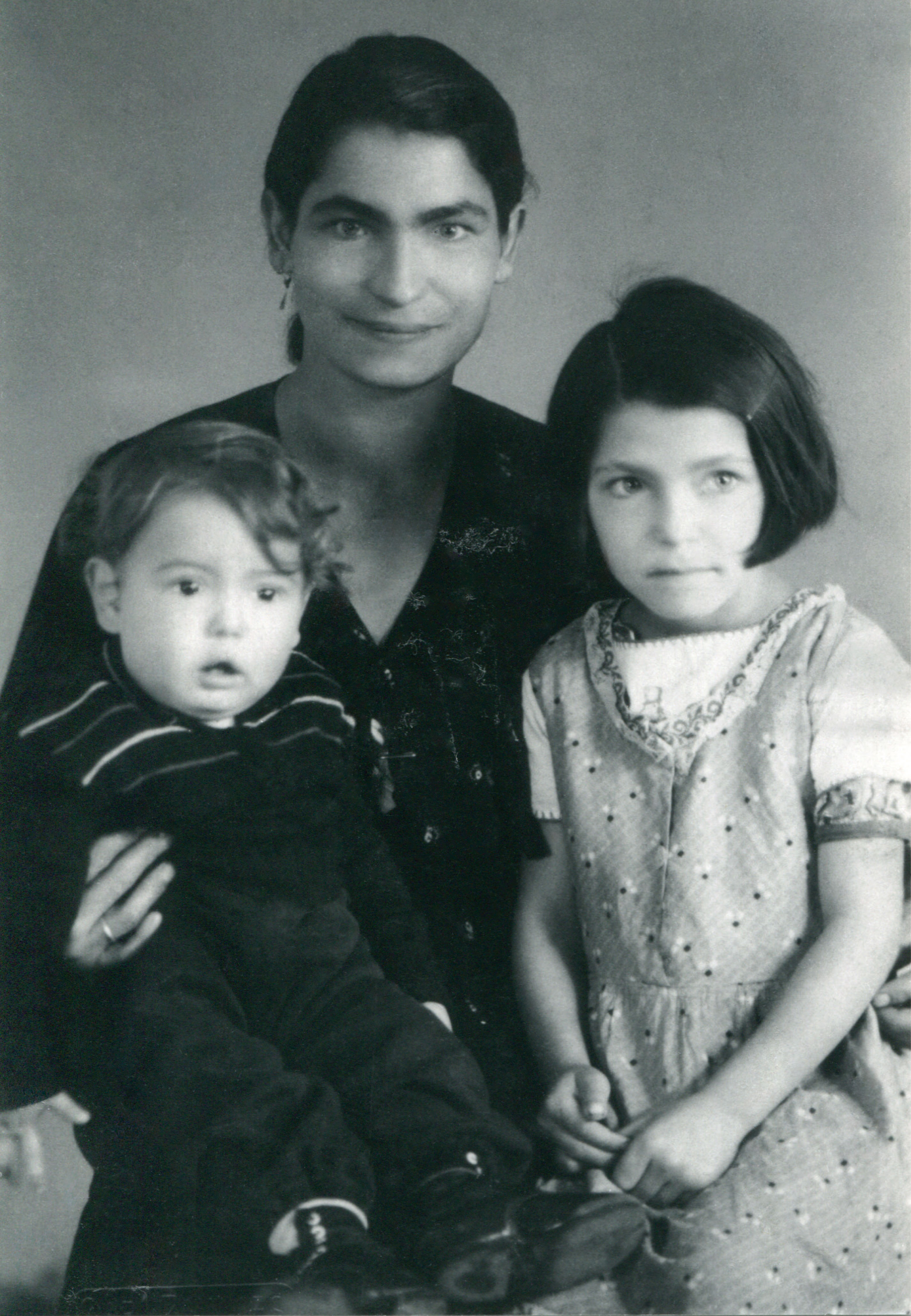 This photograph shows Auguste Laubinger and her children, Fridolin and Lydia. Auguste is looking toward the camera and smiling. Fridolin and Lydia are looking away from the camera.