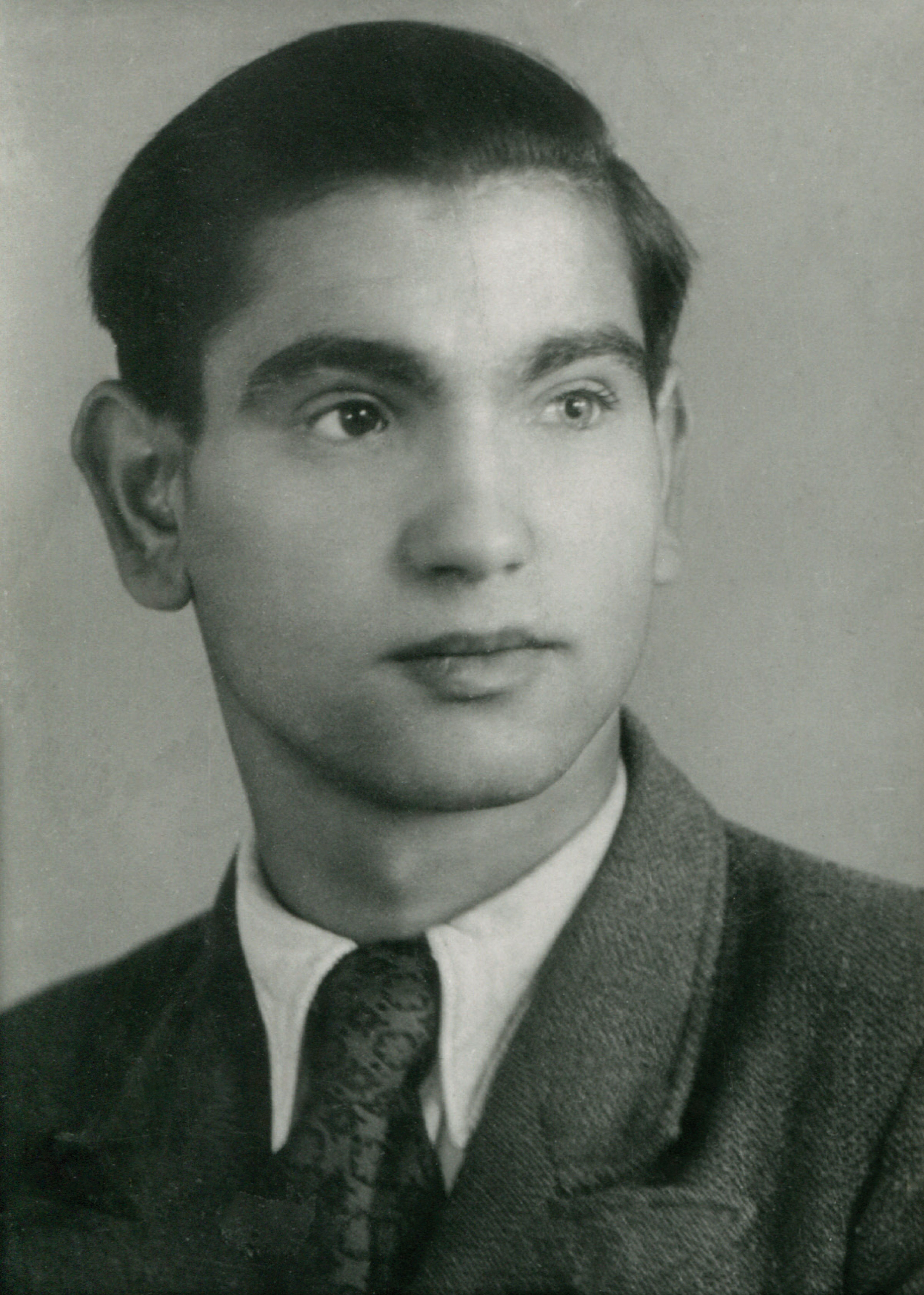 This image is a portrait photograph of Balduin Mechaus. He is a young man wearing a dark suit and necktie. His left eye is lighter than his right eye.