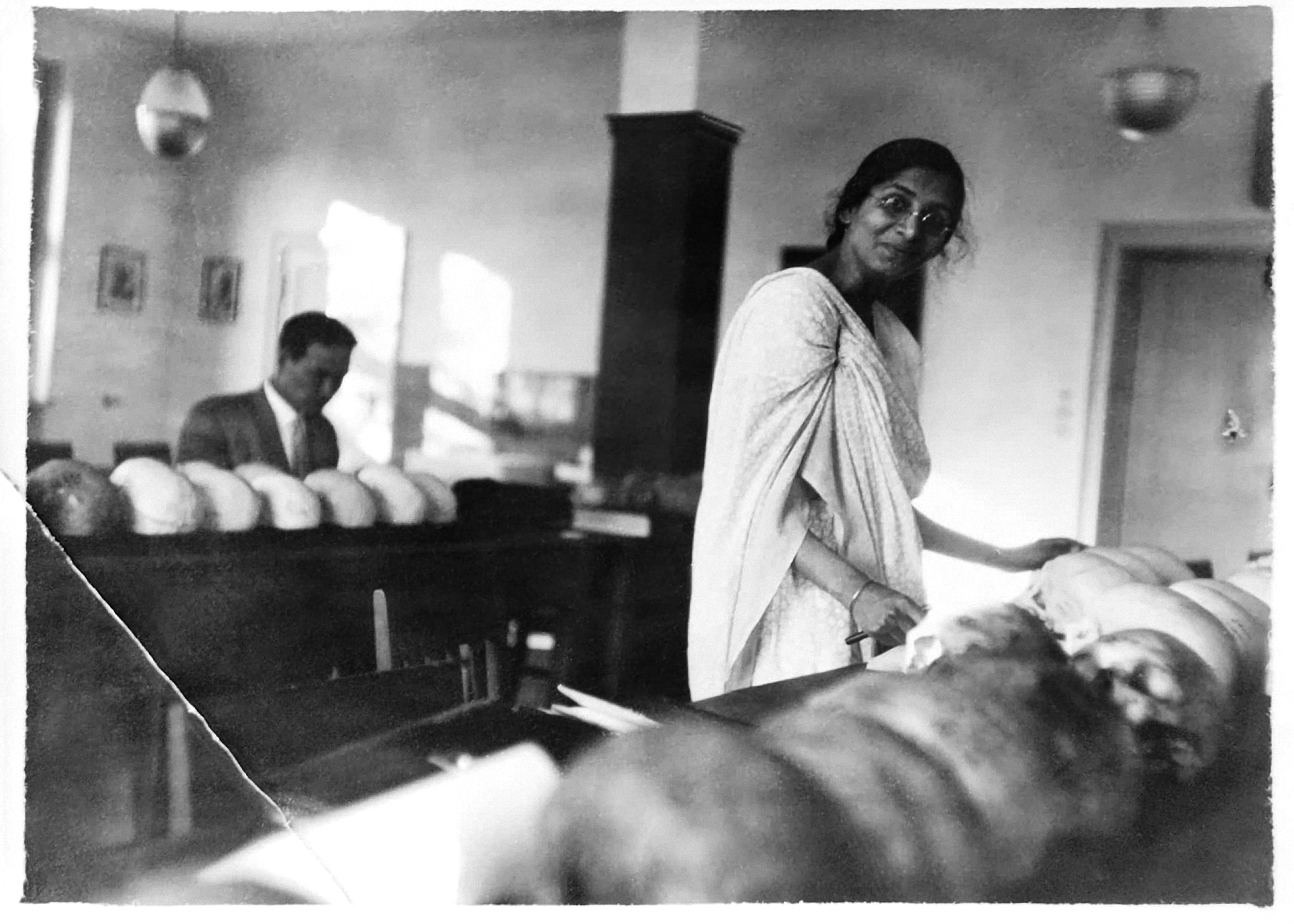 The second one is a photograph of a woman with dark skin, doctoral candidate Irawati Karvé. She is standing next to a table with a row of skulls.